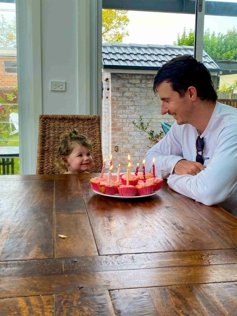 Jordan looking at Addy and smiling and she smiles back over some birthday cake and candles.