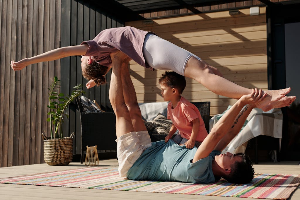 A Man Lying Down while Lifting a Woman in a family workout