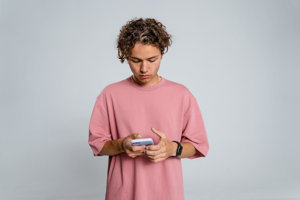 Woman in Pink Crew Neck Long Sleeve Shirt Holding Black Smartphone